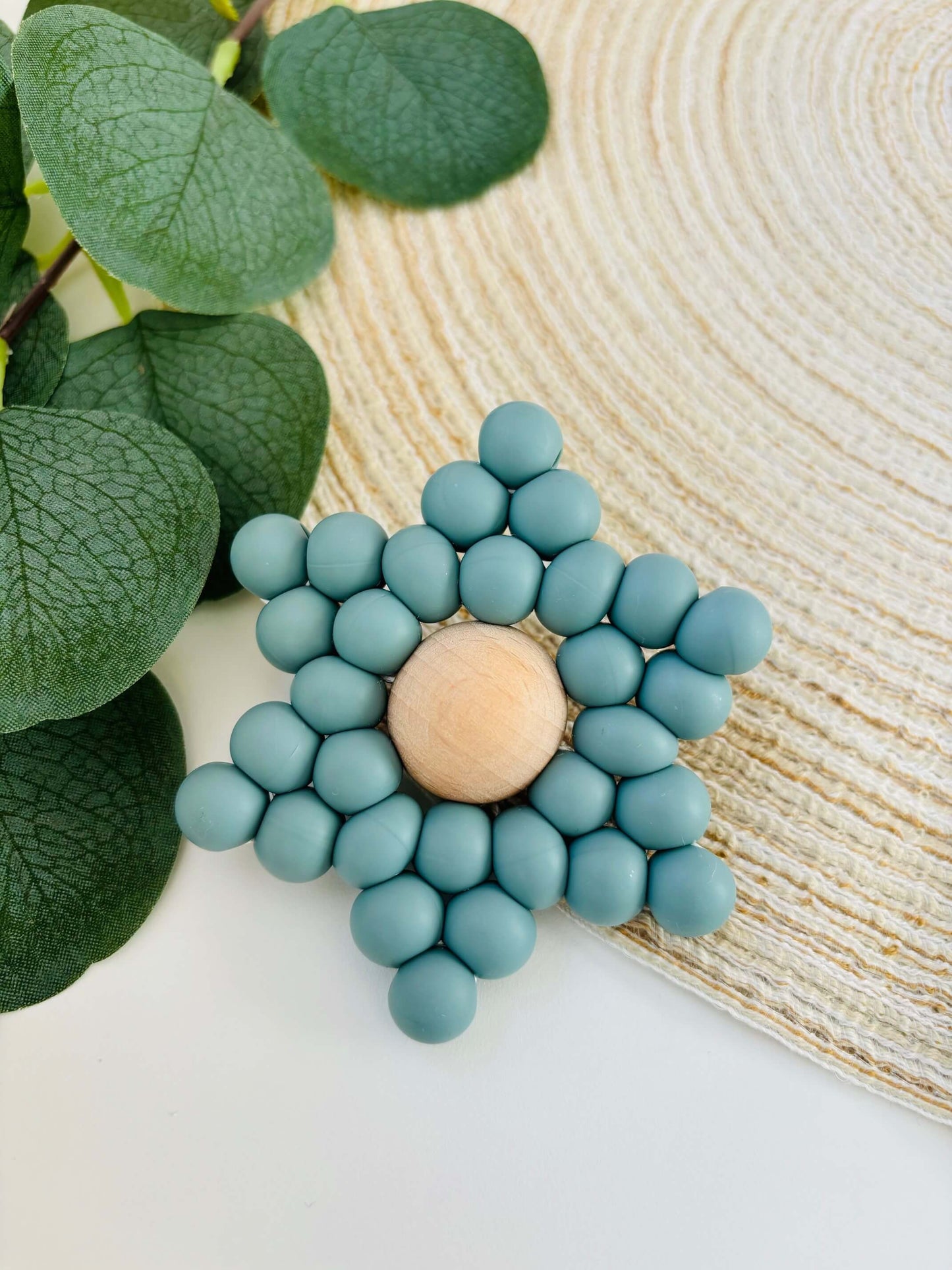 Handgemaakt bijtspeeltje in de vorm van een ster, met voedselveilige siliconen kralen in blauwgrijze kleur en een beuken houten kraal als hart.