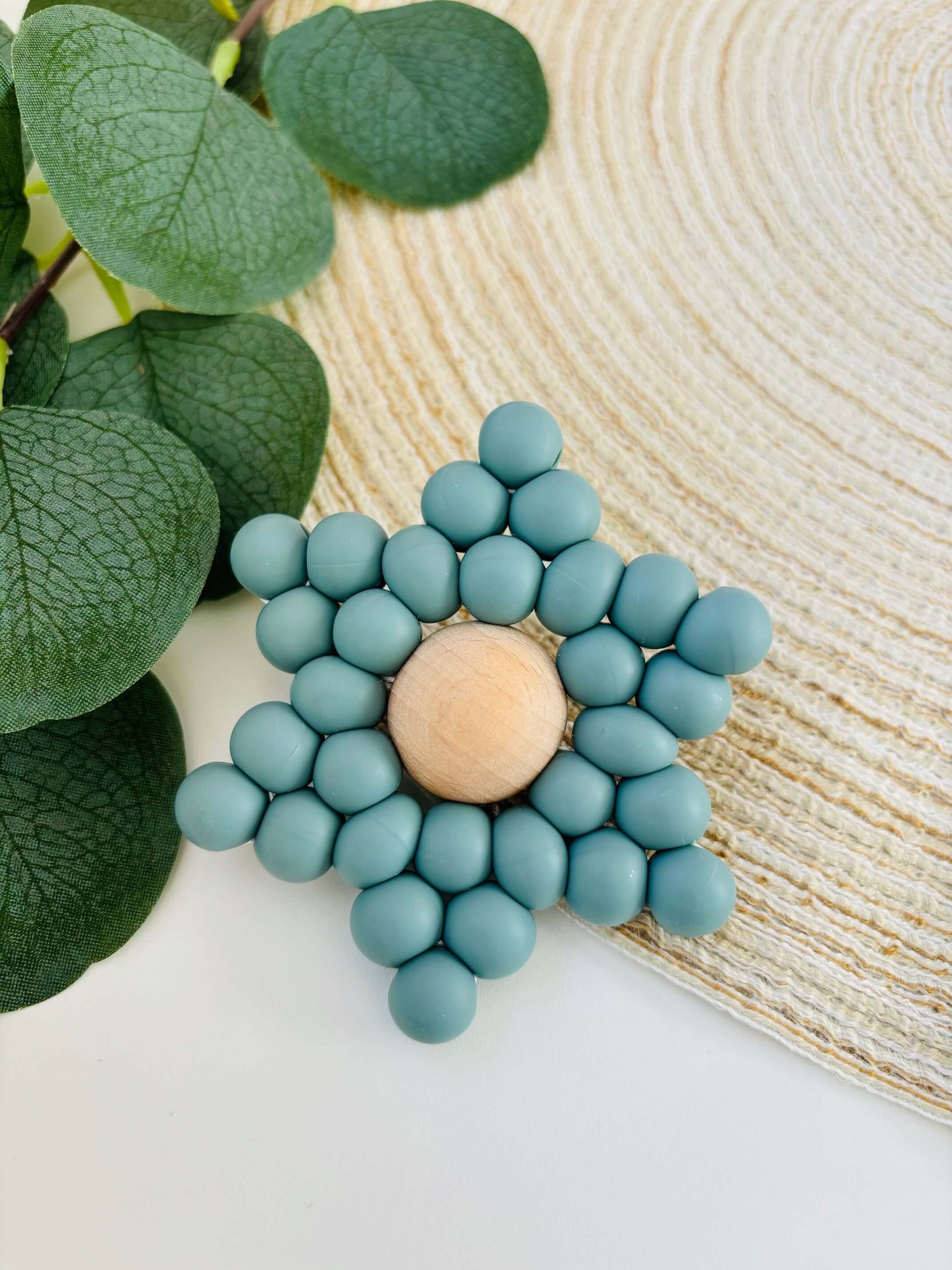 Handgemaakt bijtspeeltje in de vorm van een ster, met voedselveilige siliconen kralen in blauwgrijze kleur en een beuken houten kraal als hart.