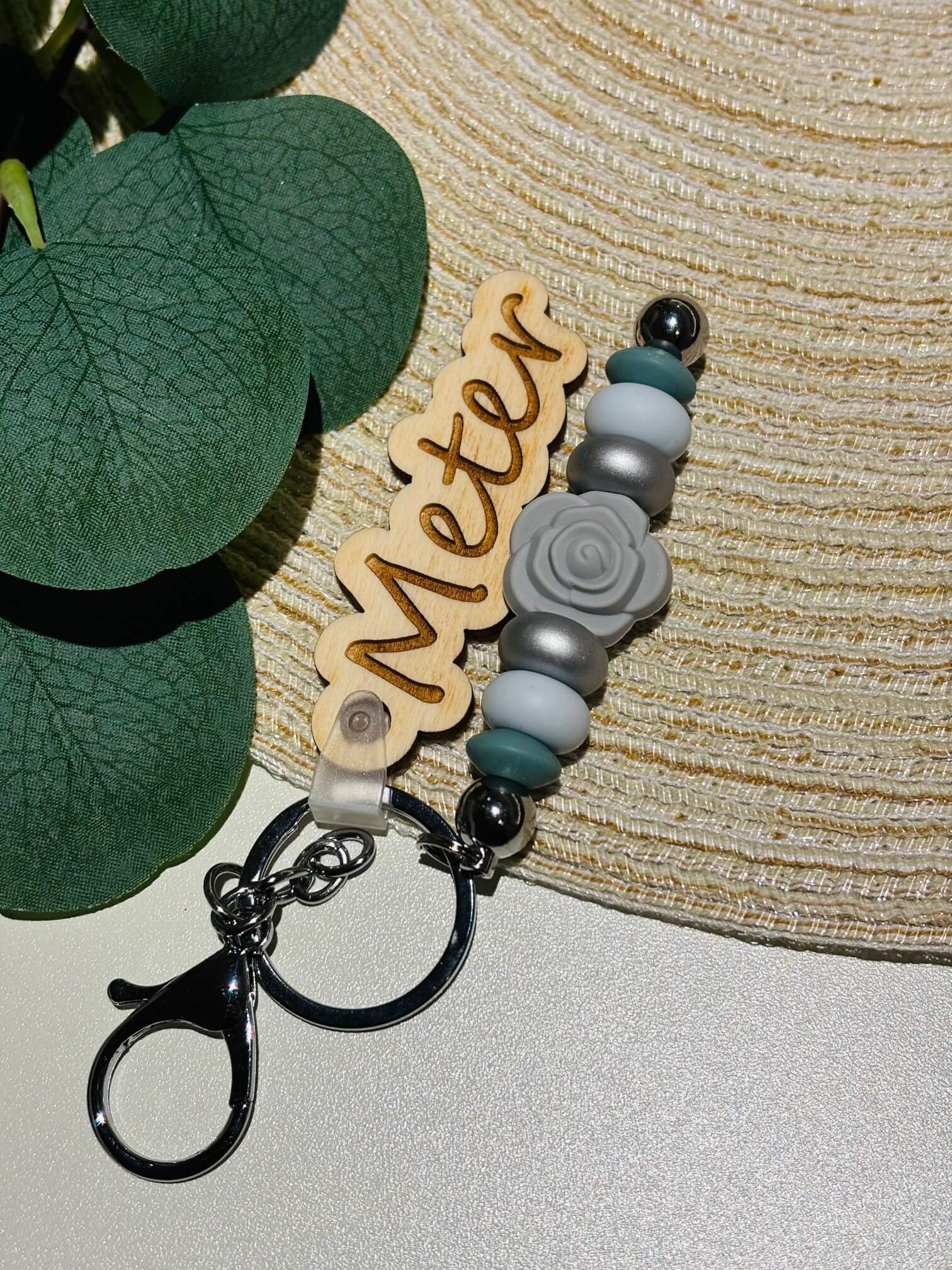 Handgemaakte sleutelhanger met siliconen kralen in winterse kleuren. Voorzien van een uit hout gelaserde naamplaatje.