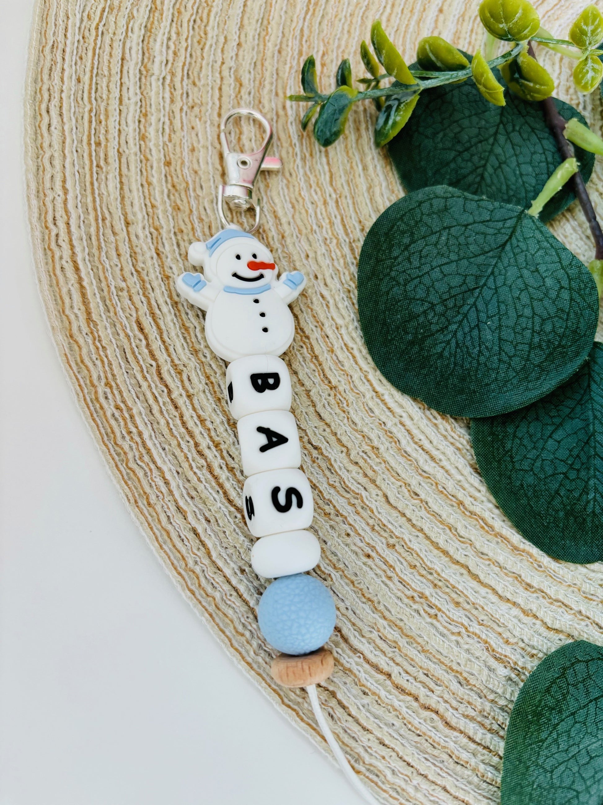 Handgemaakte sleutelhanger met naam naar keuze. Met een siliconen sneeuwpop in zacht blauw en wit, naam in witte letters.