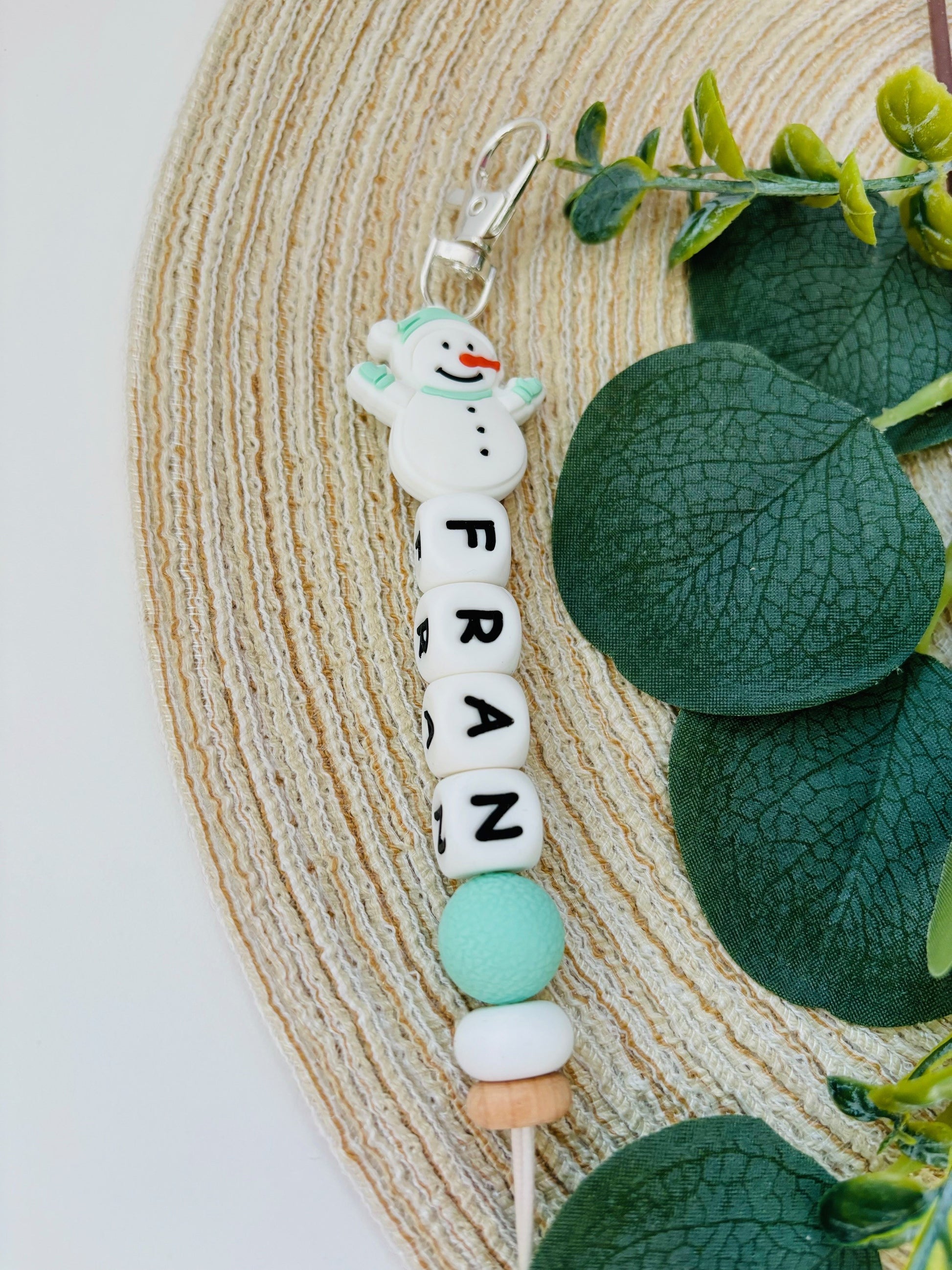 Handgemaakte sleutelhanger met naam naar keuze. Met een siliconen sneeuwpop in mint groen en wit, naam in witte letters.